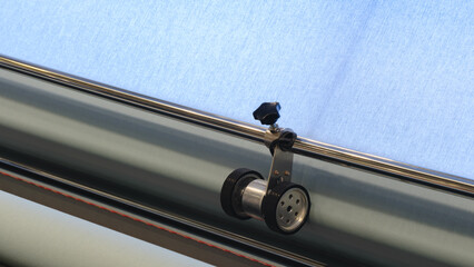 Poster - A machine is weaving a piece of fabric. The machine is made up of many parts, including a large metal piece that is connected to a hose