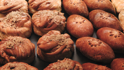 Poster - Breads on the shelf in the market or bakery. variety of pastries with different shapes and toppings. pastries are arranged in a row, with some being larger and others smaller.