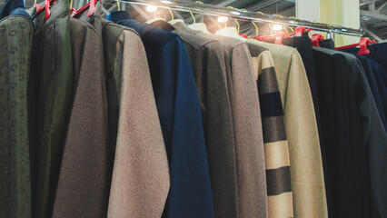 Poster - A rack of clothes with a variety of colors and styles. The clothes are hanging on a rack, and the colors include brown, blue, and green