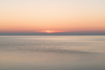 Aufkleber - Calm ocean scene at sunset, soft pastel hues of pink and orange in the sky reflecting on the water, creating a tranquil and peaceful atmosphere