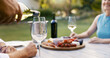© peopleimages.com - Hand, pouring wine and couple on date with romance, anniversary celebration and breakfast picnic. Elderly people, champagne and charcuterie board, bonding and marriage commitment in backyard at house