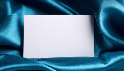 Aufkleber - blank white card rests on smooth blue fabric. shiny material softly drapes around the rectangle.