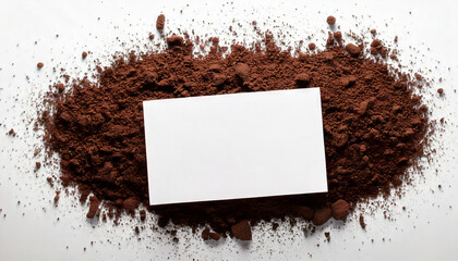 Poster - Brown powder surrounds a blank white card. Fine particles create a textured base. Space is available on the card for text or designs. Material sits on a light background.