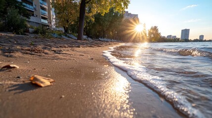 Aufkleber - Golden sunlight reflecting on water surface with sandy beach and buildings in background creating warm serene atmosphere