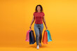 © Anastasiya - Cheerful young African American woman standing confidently holding colorful shopping bags, smiling black female in casual attire posing on vibrant yellow studio background, copy space