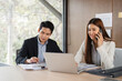 © wichayada - Business Meeting and Collaboration. Two professionals discussing financial reports in a modern office setting.