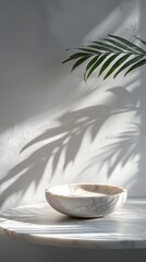 Poster - A luxurious marble table showcases the elegant contours of a bowl, while a graceful plant casts striking shadows across the surface, creating a serene atmosphere in soft afternoon light