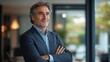 © Mitchell - Portrait of confident mature business man in suit with arms crossed corporate professional headshot