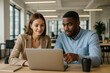 © JulieMeneghin - Jeune femme et homme regardant ensemble un ordinateur portable dans un bureau moderne, ambiance professionnelle et collaborative