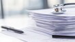 © Nice Seven - A close-up view of a stack of paperwork with a stethoscope and pen, suggesting a healthcare or medical documentation theme, health info records management.