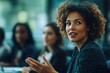 © nana - Businesswoman gesturing while talking during a presentation in front of a diverse group of colleagues