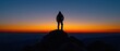 © trustmastertx - Solitary figure silhouetted against a vibrant sunset standing atop a rocky peak overlooking a vast hazy valley  The w