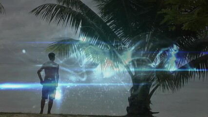 Poster - Standing by palm tree, man observing animation of abstract light patterns in sky