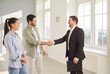 © Studio Romantic - Happy smiling young couple customers shaking hands with professional man realtor making deal buying property standing in new flat. Family ready to become homeowners. Real estate market concept