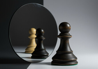 Poster - Pawn chess piece reflecting in mirror showing another pawn chess piece on black and white background. Dark pawn chess piece standing on the white surface