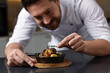 © New Africa - Professional chef serving dish at table indoors, selective focus