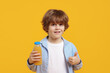 © New Africa - Little boy with drink showing thumbs up on orange background