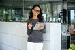 © Dorde - Confident Asian Woman Holding Tablet in Bright Modern Office with Glass Walls