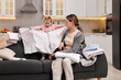 © New Africa - Housewife with her little daughter folding laundry on sofa at home