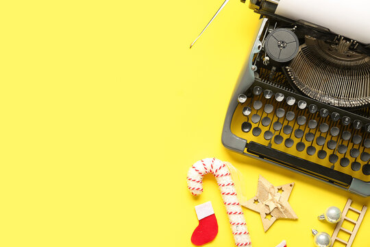 Vintage typewriter with blank paper and Christmas decor on yellow background
