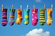 © trustmastertx - Colorful socks hanging on a clothesline against a bright blue sky with fluffy clouds  A cheerful and whimsical scene