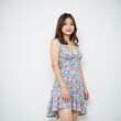 © SimpleDesignStudio - A young Asian woman in a floral dress stands confidently against a plain background, showcasing her personal style and vibrant fashion choice.