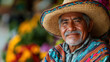 © Rajesh - An older indigenous Mexican man smiles warmly, wearing vibrant clothing and a straw hat