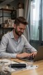 © Tatyana - Young man smiling while working on a laptop in a cozy office