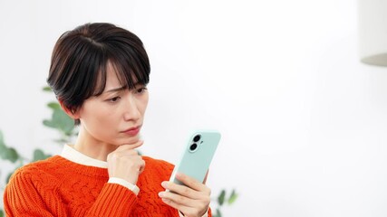Aufkleber - リビングルームで悩みながらスマホを見るミドル女性