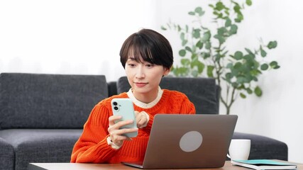 Leinwandbilder - スマホとノートパソコンで作業するミドル女性
