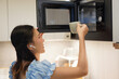 © pixs4u - asian woman using microwave oven in modern kitchen