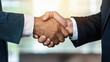 © natcha - Two business professionals shaking hands in formal setting, symbolizing successful summer business deal or partnership
