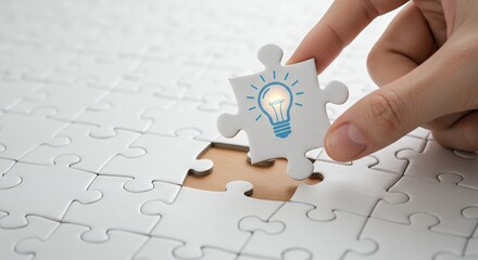 Poster - Hand completing white jigsaw puzzle with light bulb piece for new idea