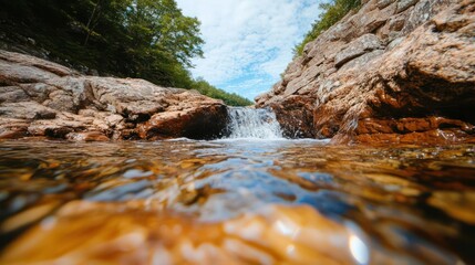 Poster - Close up view of small waterfall cascading over rocks with clear water reflections and lush green foliage under a blue sky