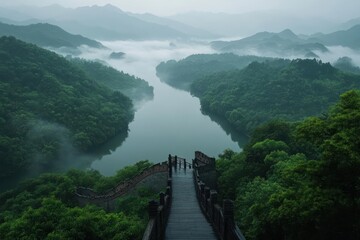 Poster - Aerial view of lush green mountainous landscape with a river winding through the valleys. Misty fog covers the hills creating a serene natural environment