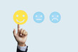 © AREE - A businessman's hand reaches out to touch a smiley face icon to express satisfaction or feedback on a product or service or to express a feeling of being happy at work.