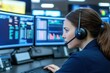 © Cheewynn - A focused professional wearing a headset monitors multiple computer screens displaying data and analytics in a modern control center.
