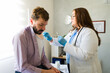 © AntonioDiaz - Caucasian doctor wearing gloves and lab coat giving an injection to a male patient in a medical office