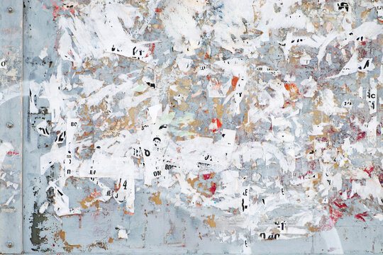 grunge textured rough gray metal wall with torn posters and announcements. abstract background