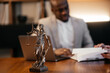 © Валерия Стоганенко - The Statue of Justice symbol on wooden table, legal law concept. Consultation and conference of lawyers at law firm in office. Professional business people on blurred background