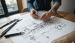 © Nata - Architect working on a detailed architectural plan with drawing tools on a wooden table