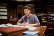 © Marko Geber - Portrait of a smiling male student at library table with open books