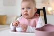 © New Africa - Cute little baby with bottle on feeding chair at home