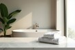 © Jiraporn - Clean white towels neatly stacked on a marble surface in a bright bathroom with a bathtub and plant