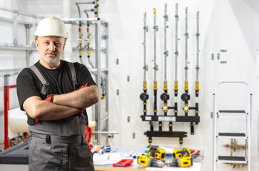 Poster - man who repairs plumbing equipment. construction stands with hands clasped. old repairman in gray ov