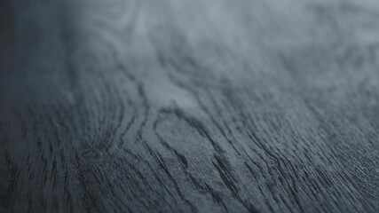 Slow motion handheld shot of black painted oak surface