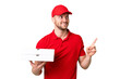 © luismolinero - Pizza delivery man with work uniform picking up pizza boxes over isolated chroma key background pointing up a great idea