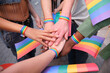 © Ladanifer - Diverse people joining hands at a LGBT pride parade, showing rainbow bracelets and flags, celebrating diversity and equality