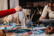 © qunica.com - Two individuals engaged in a shared painting activity, using art supplies on a table in a cozy setting, fostering artistic creativity and collaboration.