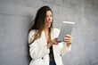 © javiindy - A shocked woman is reacting to breaking news she is reading on her tablet against a gray wall